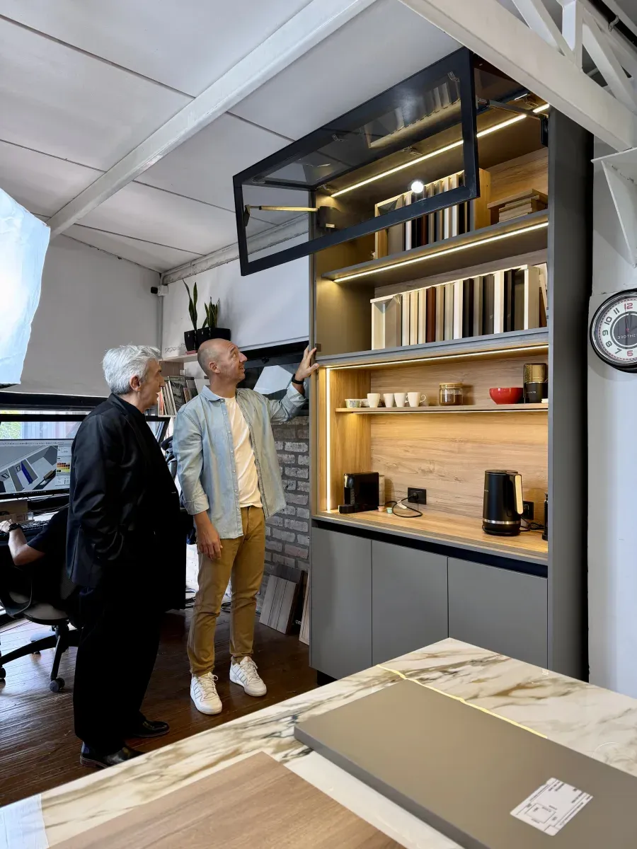 Un integrante de Brothers le muestra a un cliente un mueble alacena iluminado en el showroom