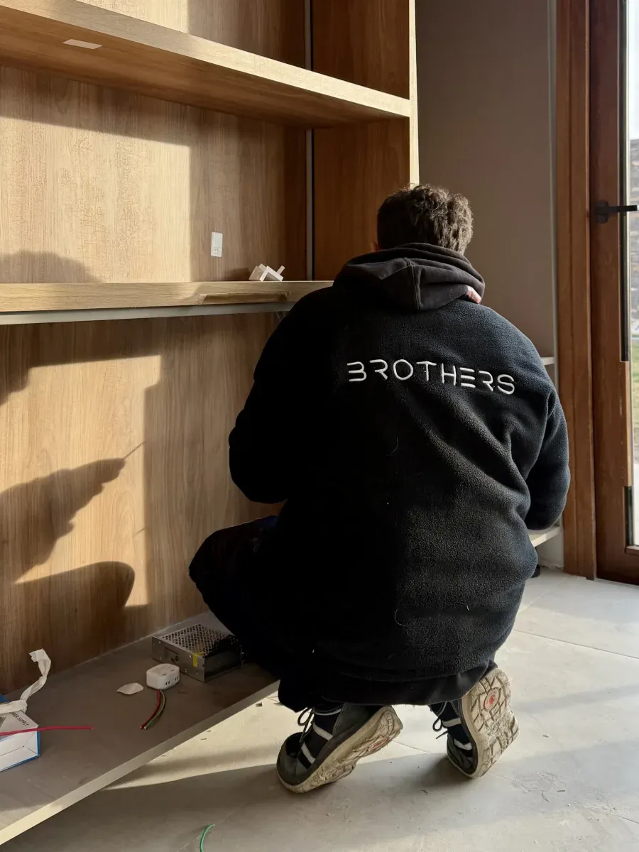 Instalador de Brothers ajusta la parte baja de un mueble de madera en la obra