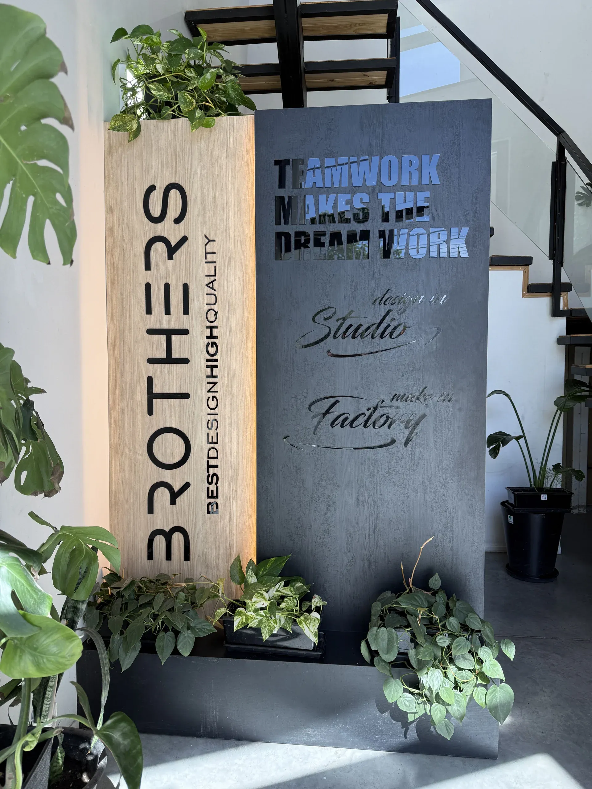 Recepción de Brothers: el cartel de la marca en madera y metal, rodeado de plantas
