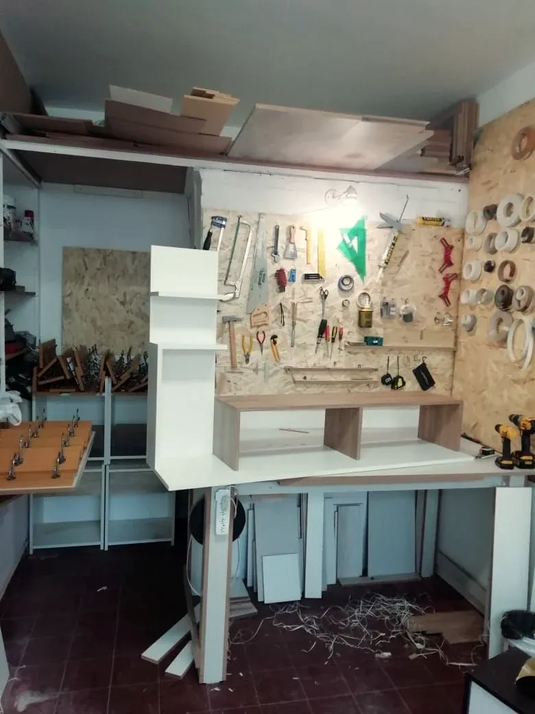 El primer taller de Brothers: un ambiente chico con herramientas colgadas en la pared y un mueble blanco en armado