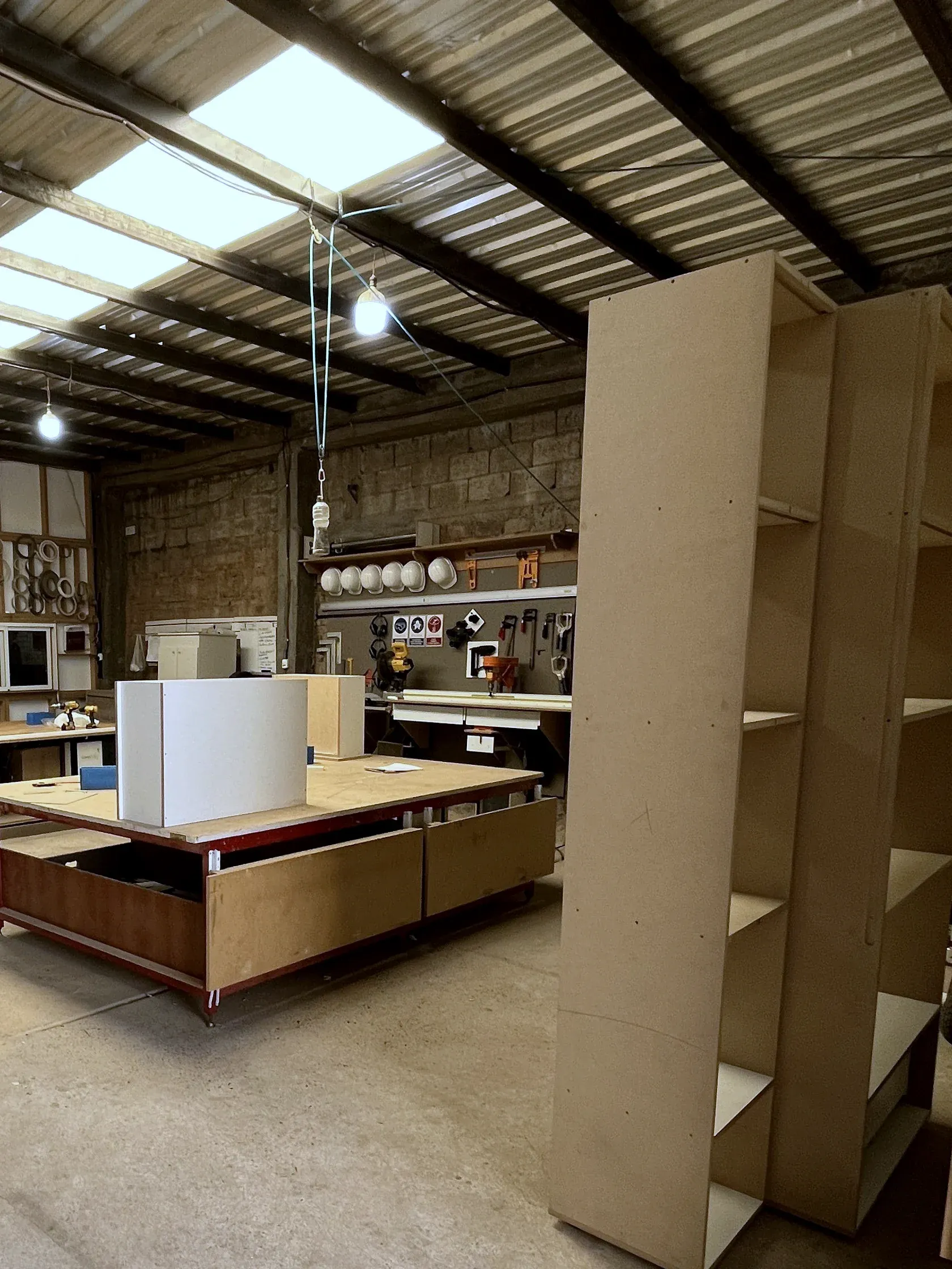 El segundo taller: una nave con techo de chapa, una mesa de armado grande y módulos en fabricación
